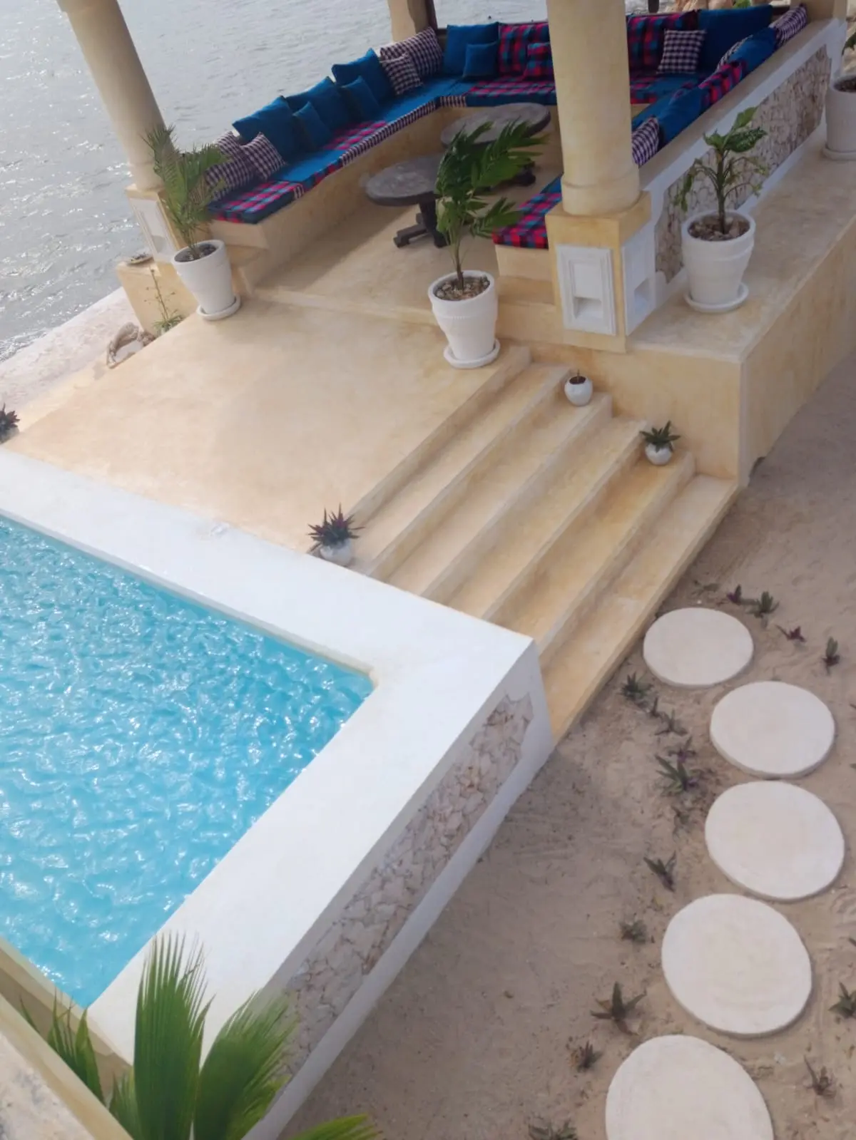 Aerial view of luxury infinity pool with traditional seating and ocean backdrop
