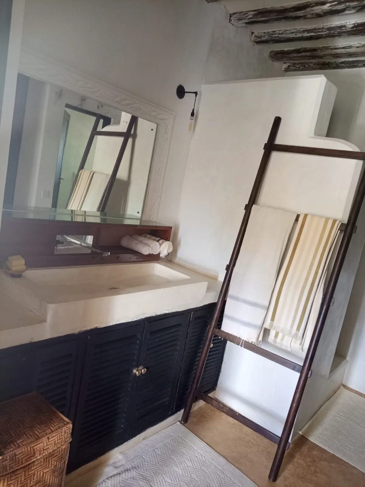 Bathroom with stone sink, mirror and wooden towel ladder