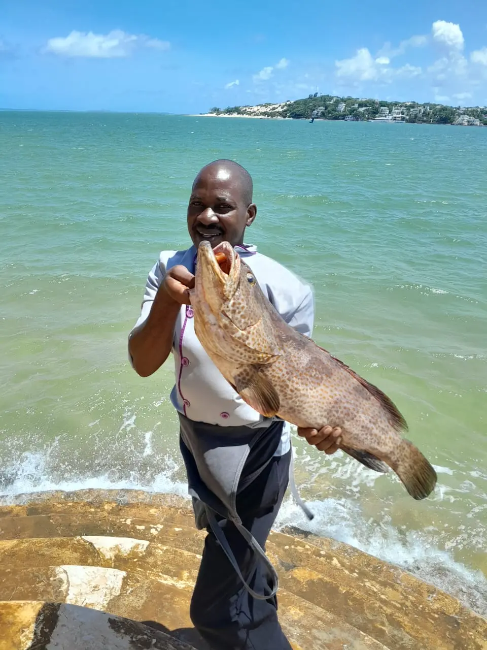 Chef displaying fresh caught fish on the beach with ocean view