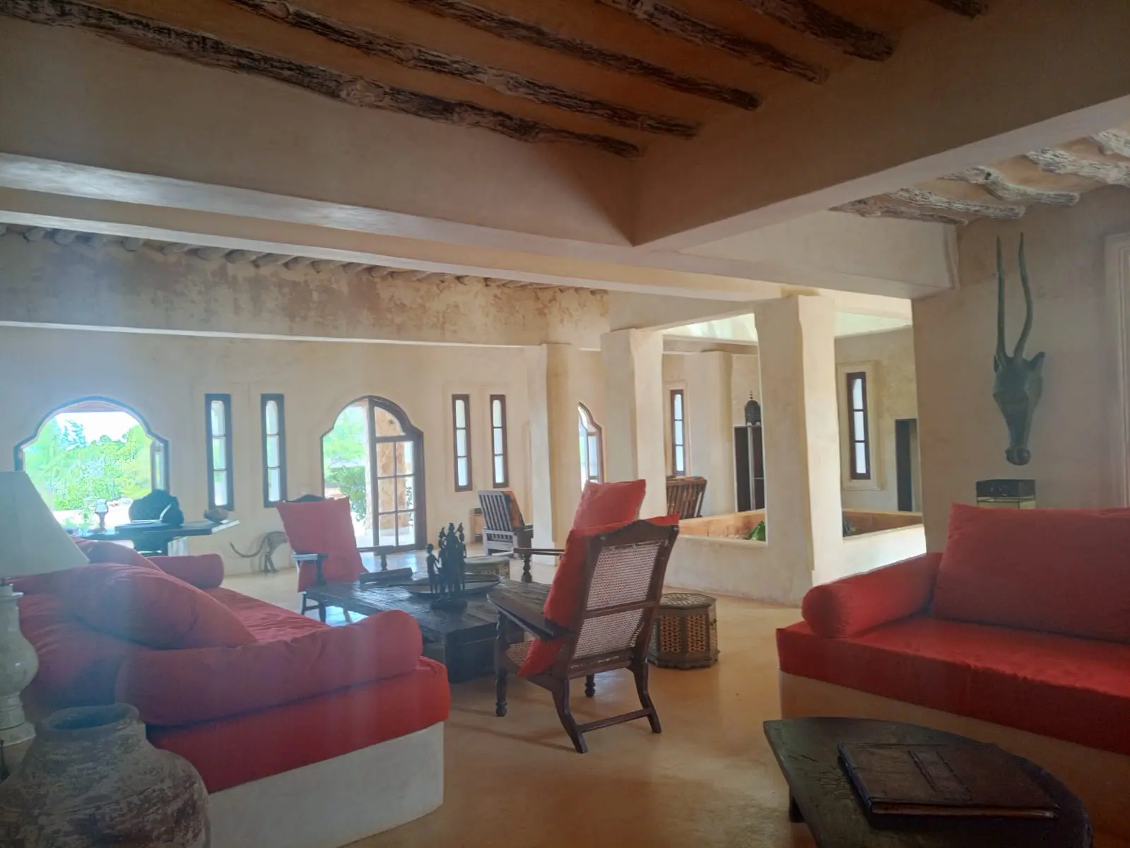 Grand living room with red cushioned seating and traditional carved furniture