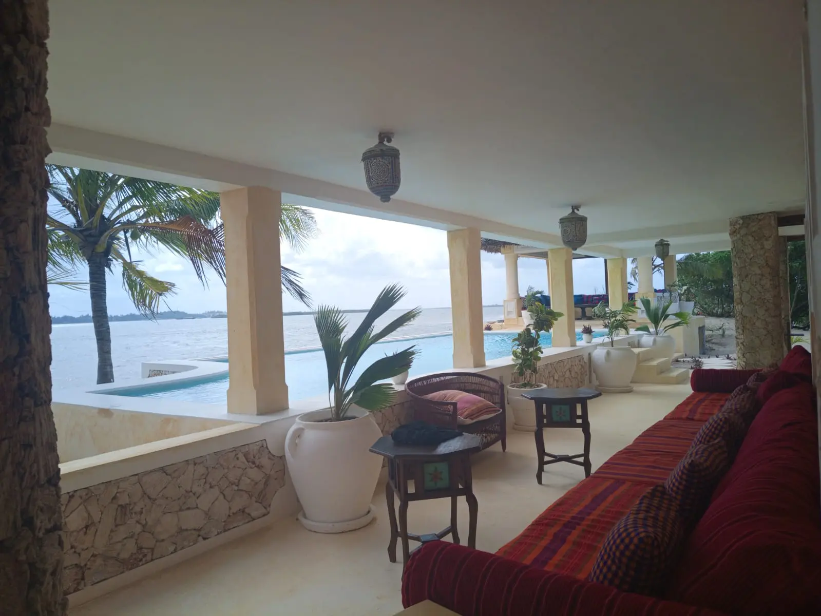 Covered terrace overlooking infinity pool with traditional lanterns and ocean views